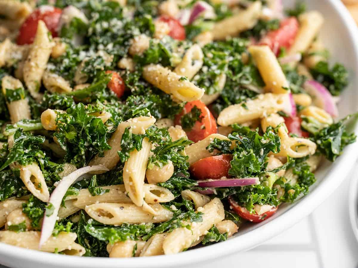 Close up side view of a bowl full of big kale pasta salad.