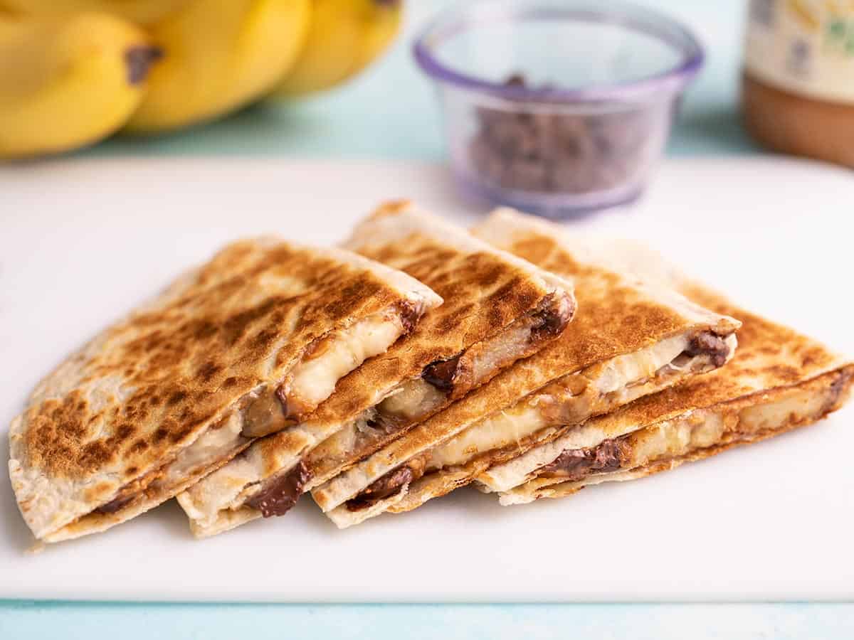 Peanut Butter Banana Quesadillas lined up on a cutting board.