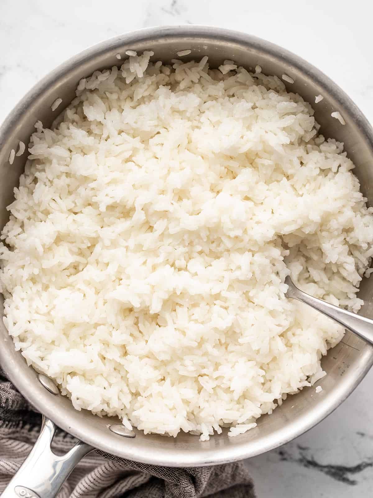 Close up of cooked rice in a pot with a fork.
