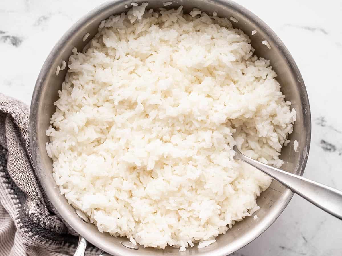 Cooked rice in a saucepot with a fork.
