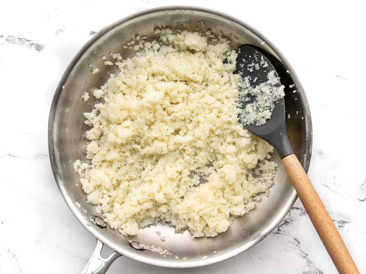 Cauliflower rice in a skillet with a spatula