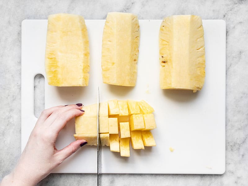 Pineapple quarter being cut into chunks