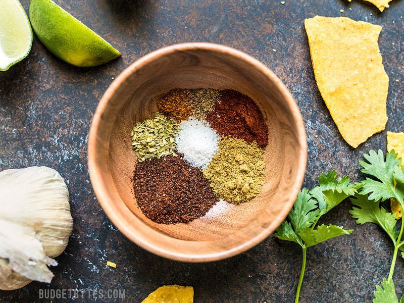Individual spices used for homemade taco seasoning in a small wooden bowl. 