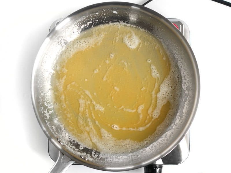 Golden brown butter solids in the skillet full of melted butter, foam is subsiding.