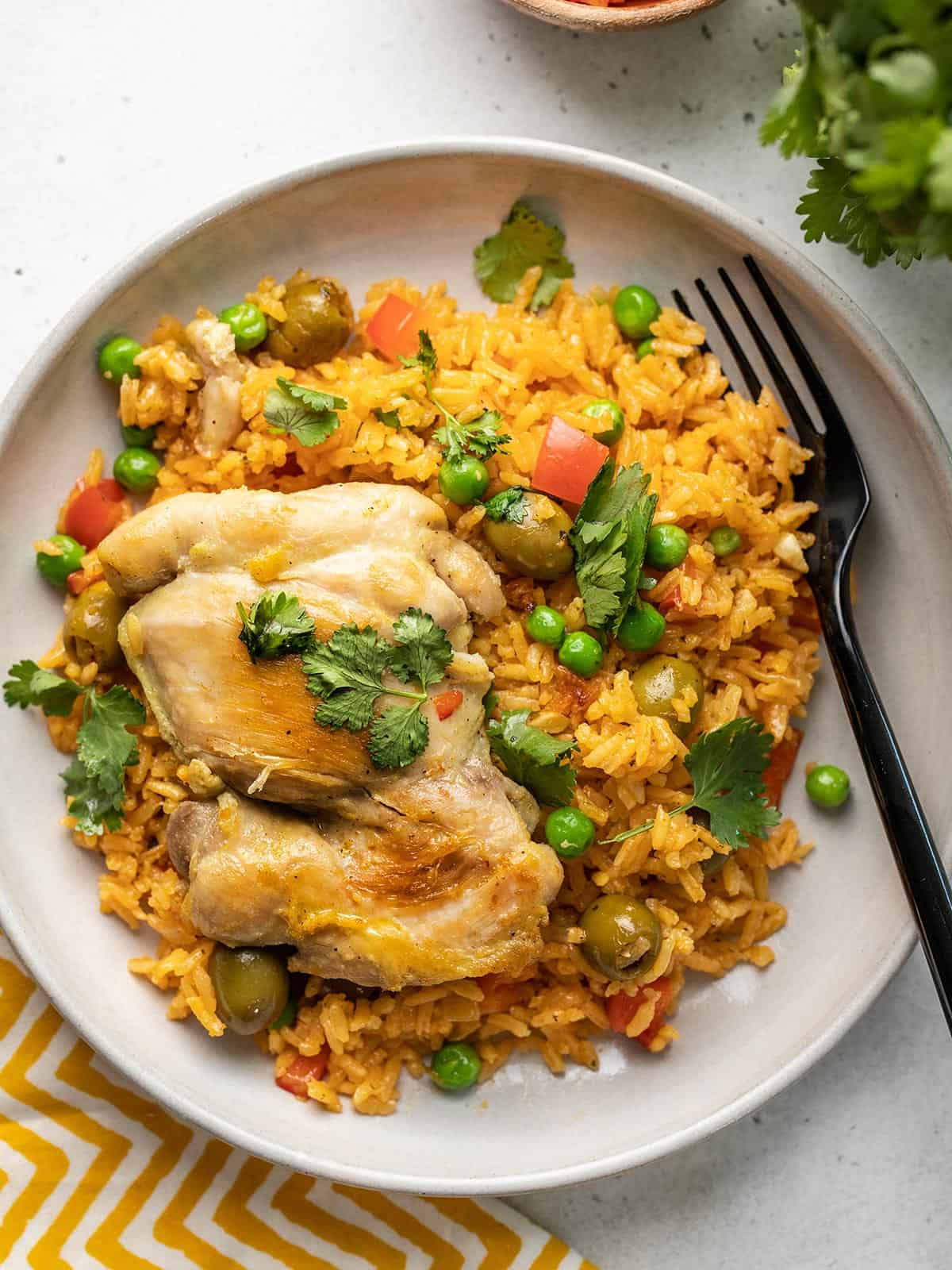 Arroz con pollo on a white dish with a black fork in it.