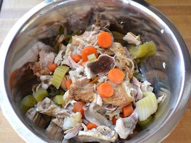 Large pieces of veggies and chicken taken out of slow cooker with slotted spoon 