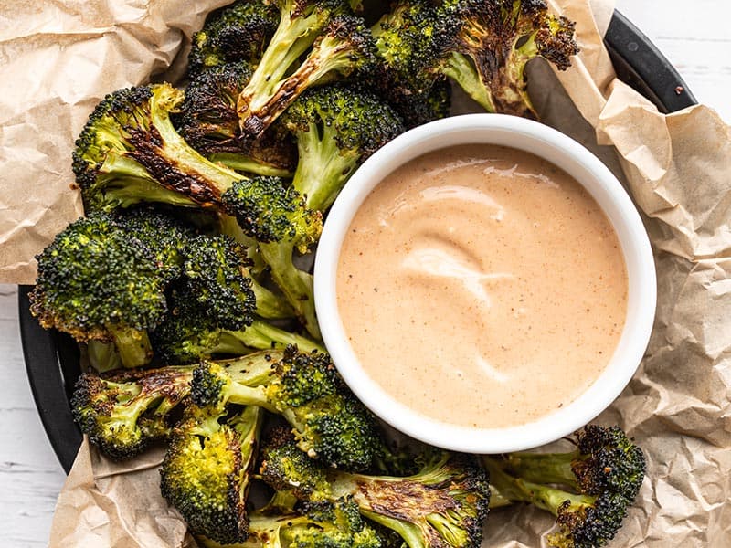 A bowl of comeback sauce surrounded by roasted broccoli