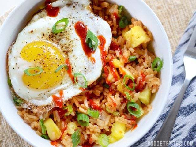Close up overhead view of a pineapple sriracha breakfast bowl with a fried egg on top