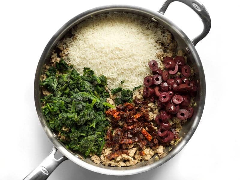 Add rice, spinach, olives, and sun dried tomatoes to skillet