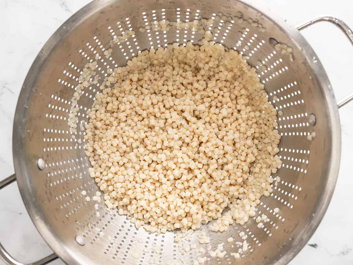 Cooked couscous draining in a colander.