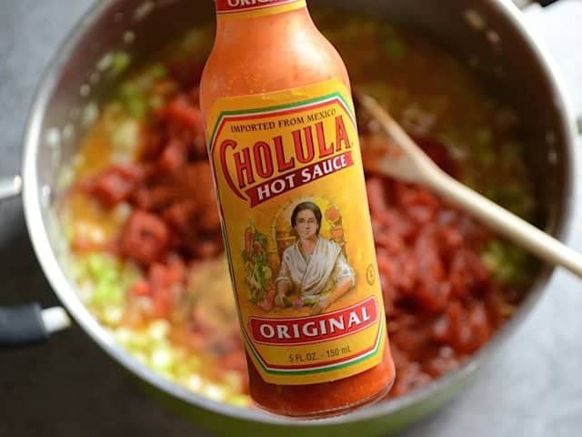 Cholula Hot Sauce shown to be poured into pan of ingredients 