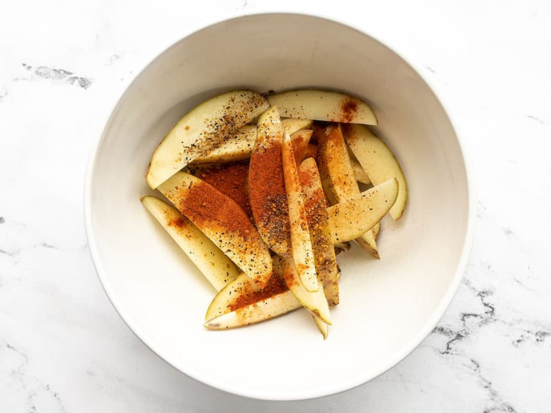Potato wedges with seasoning in a bowl