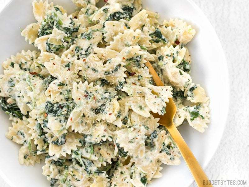 Spinach Artichoke Pasta on white plate with gold fork 