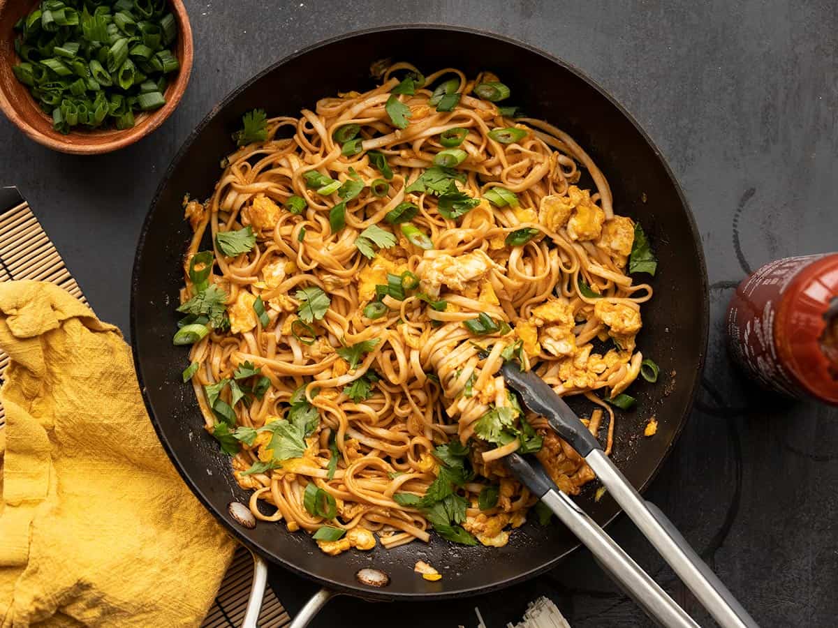 spicy sriracha noodles in a skillet with tongs