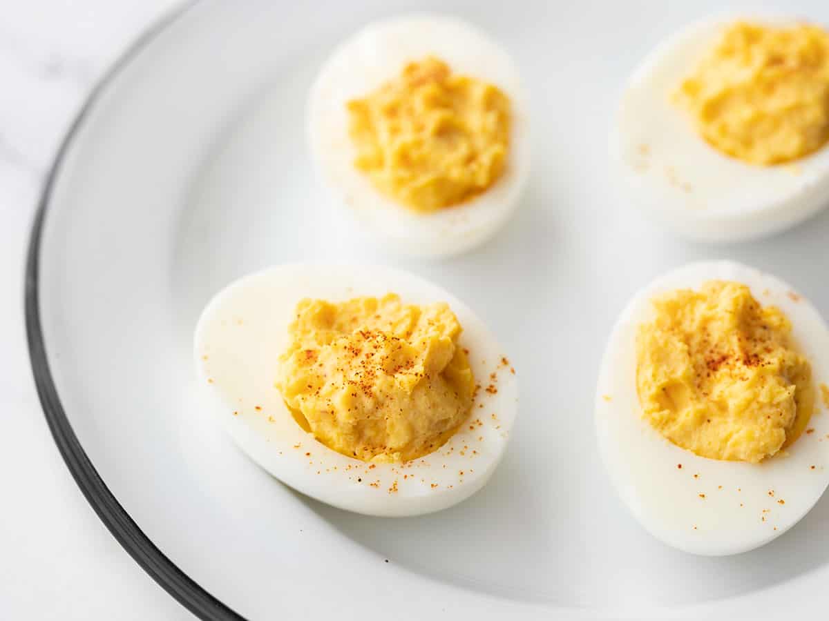 Side view of four deviled eggs on a white plate