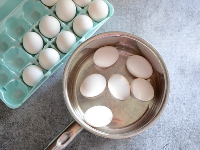 Eggs in Pot with container of remaining eggs on the side 