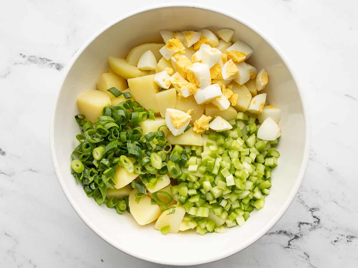 Potatoes, eggs, green onion, and celery in a bowl