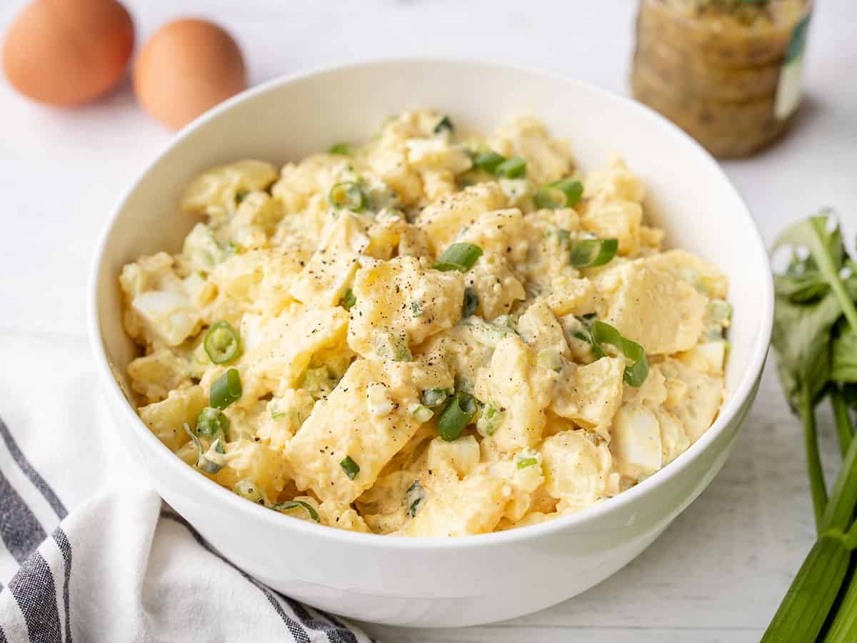 Finished potato salad in a serving bowl with ingredients on the sides