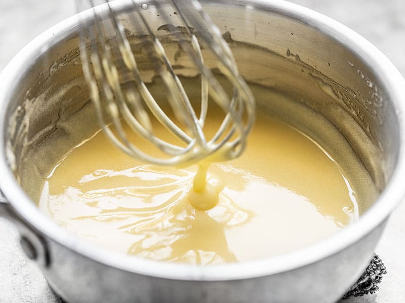 Finished lemon curd dripping off the whisk into the sauce pot. 