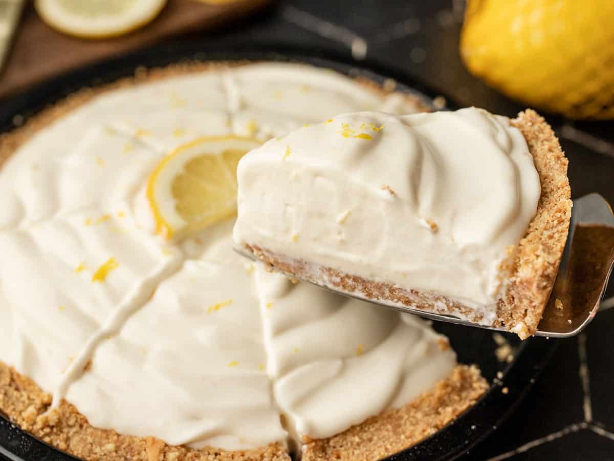 Side view of a slice of lemon cream pie being lifted from the pie plate
