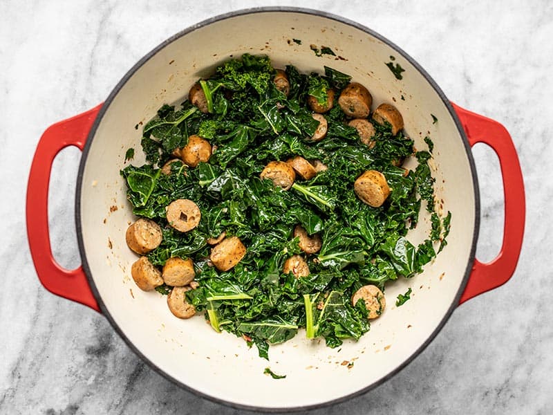 Wilted kale with chicken sausage in the pot.