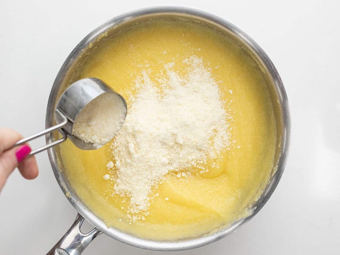 Grated Parmesan being sprinkled over the cornmeal.