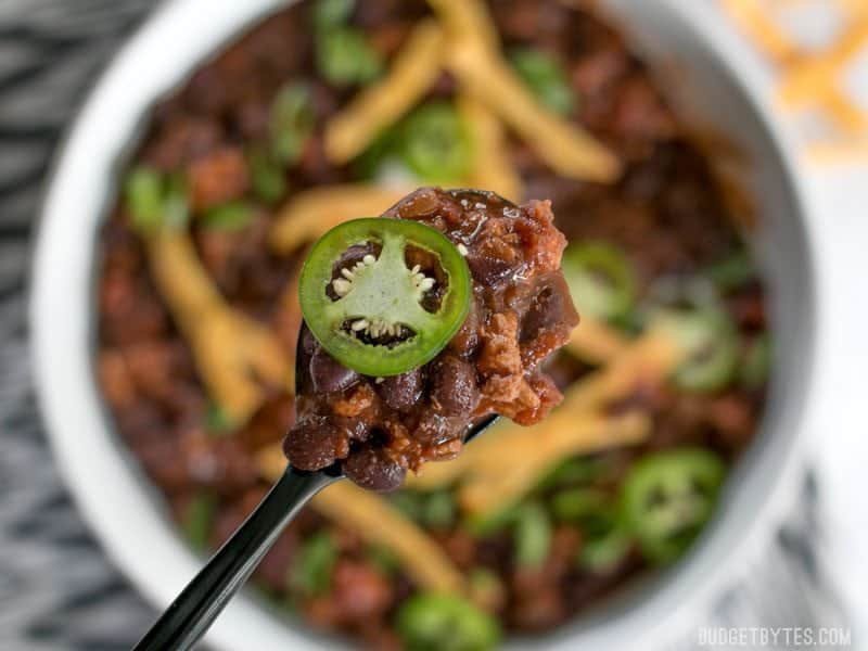Close up of a spoonful of Weeknight Black Bean Chili with the bowl in the background. 