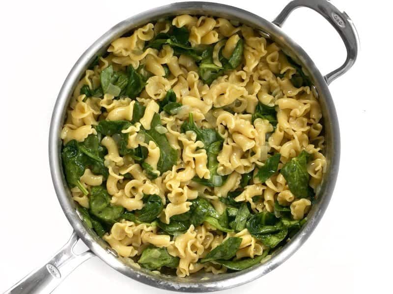 Spinach added to skillet with cooked pasta 