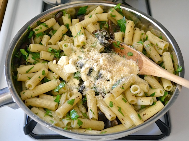 parmesan cheese added to top of pasta dish in skillet 