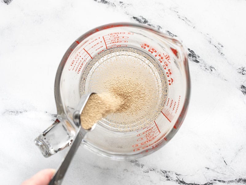 yeast being added to a measuring cup with water