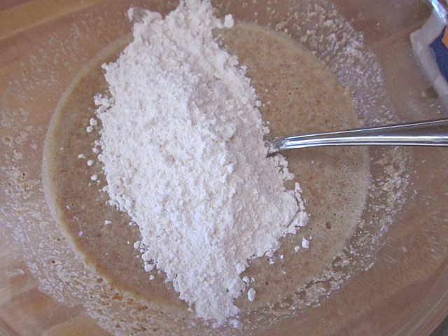 all purpose flour being added to wet ingredient mixture in bowl