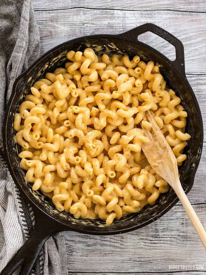 Finished skillet mac and cheese in a cast iron skillet on a wooden table with a wooden pasta fork