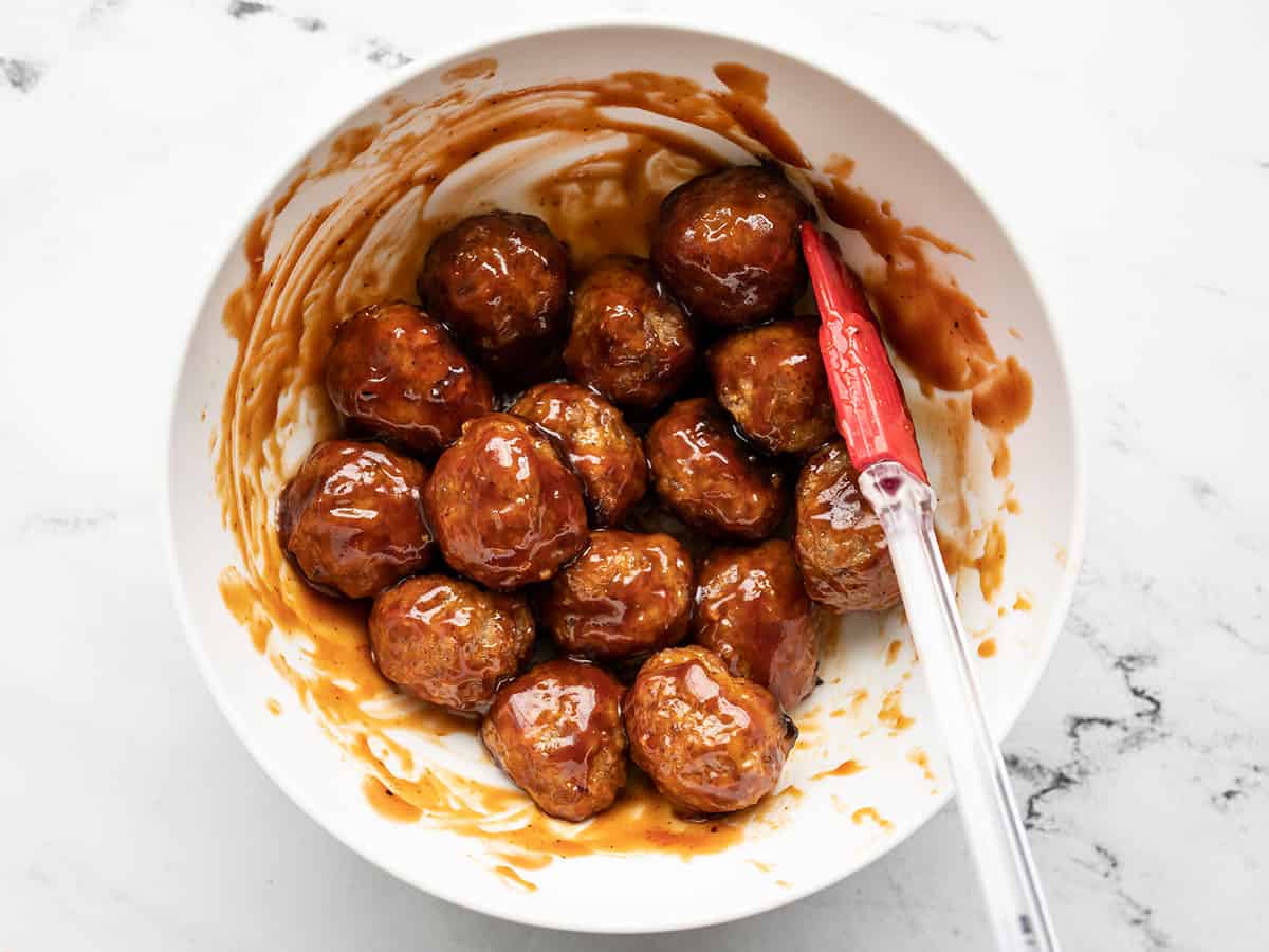 BBQ sauce coated meatballs in a bowl with a spatula
