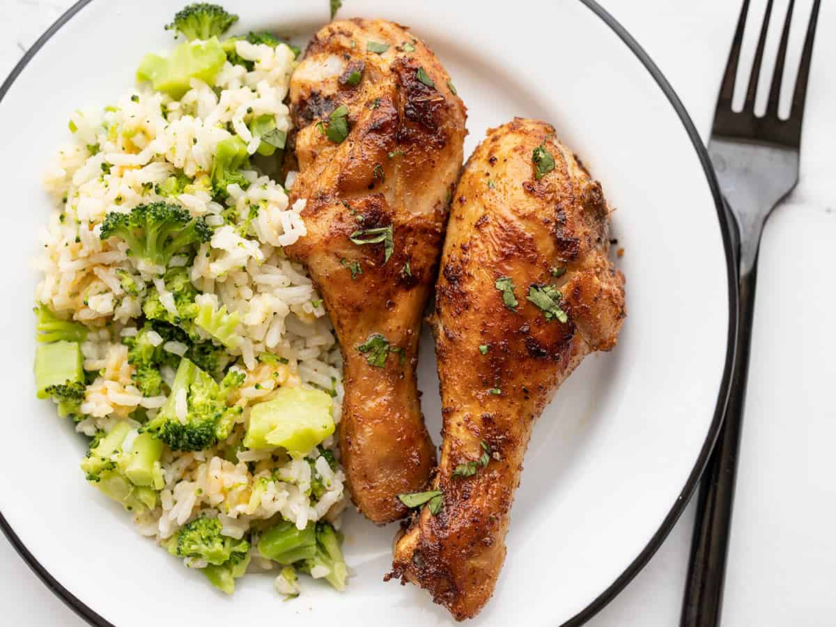 Baked chicken drumsticks on a plate with easy cheesy broccoli and rice