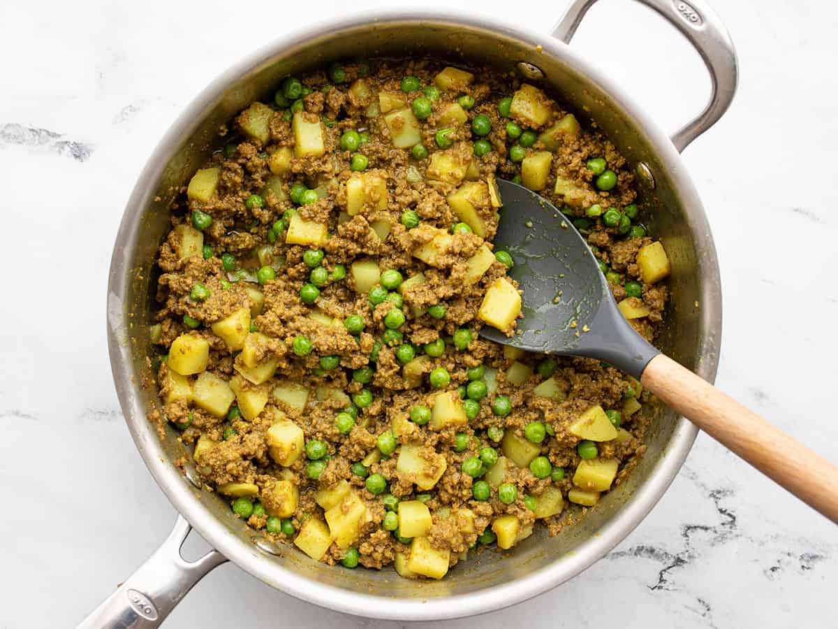 Finished curried beef with peas in the skillet with a spatula