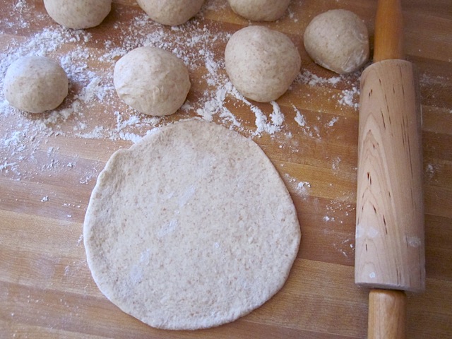 cut pieces of dough rolled into balls and then rolled out, with rolling pin on the side