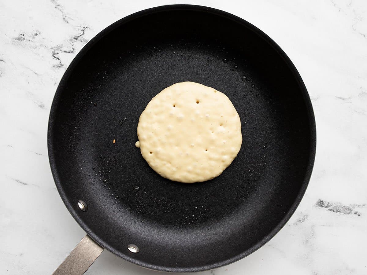 Half cooked pancake in the skillet.