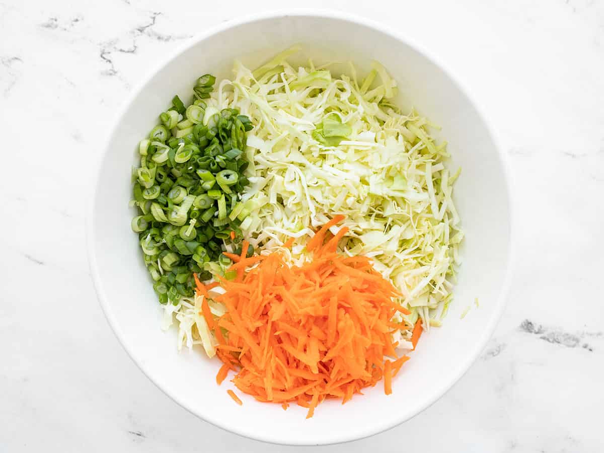 Shredded cabbage, carrots, and sliced green onion in a bowl