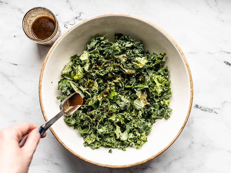 Balsamic Vinaigrette being drizzled over kale in a bowl