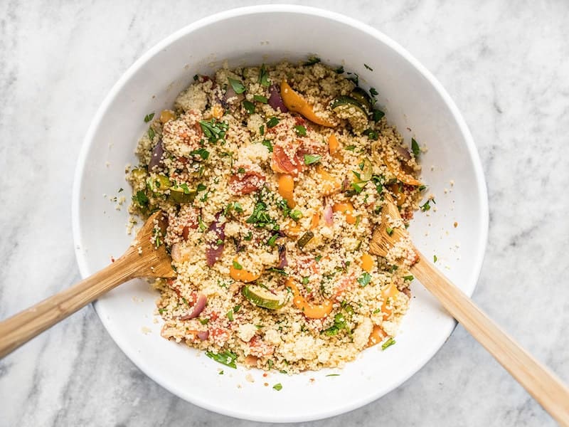 Finished Roasted Vegetable Couscous in a bowl with two wooden spoons
