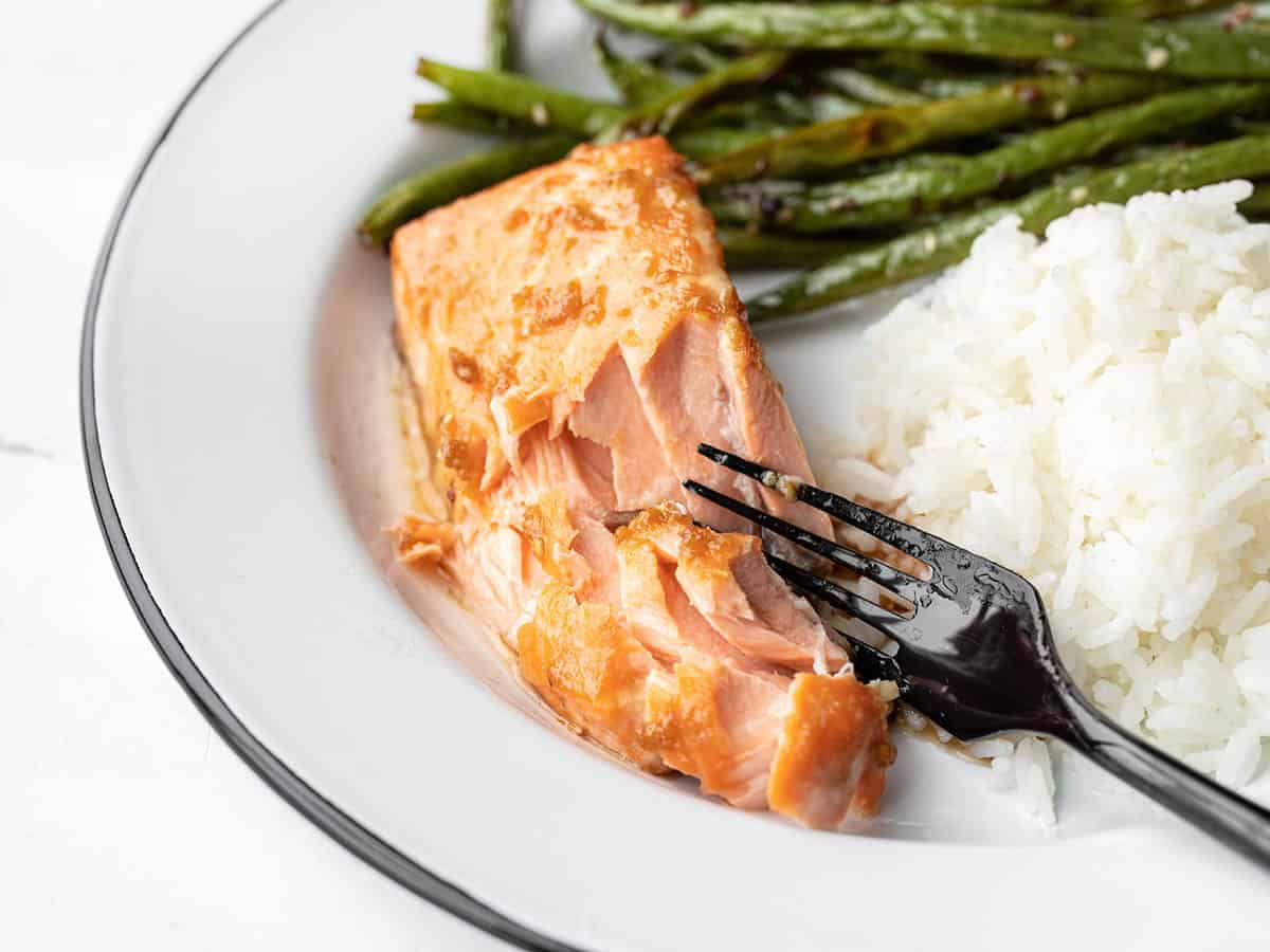 Side view of baked ginger salmon on a plate with green beans and rice