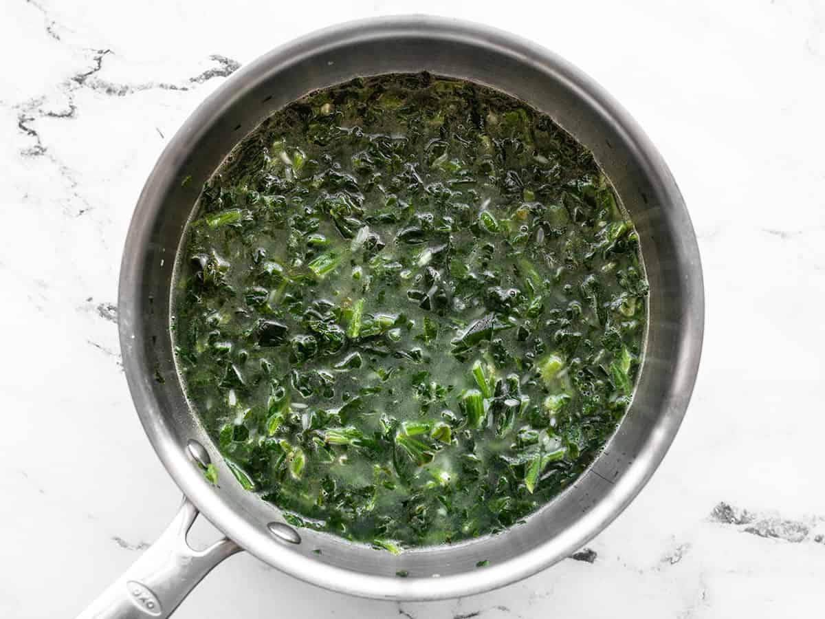 Stirred rice spinach and water in the saucepot