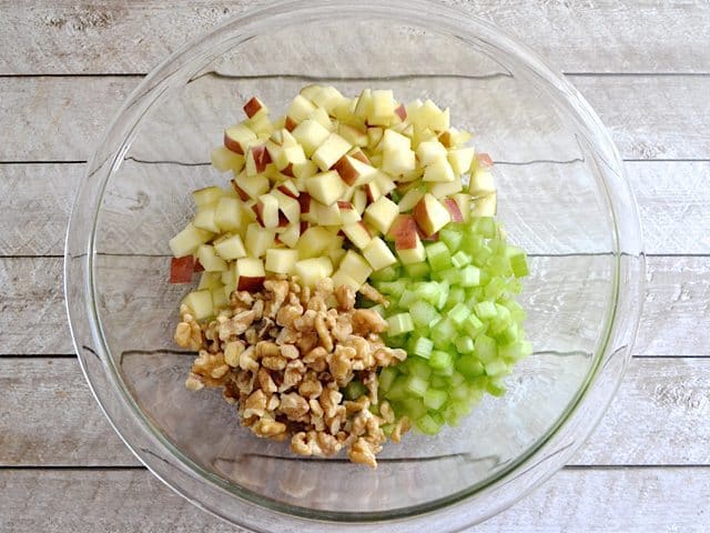 Chopped apple, celery and walnuts in mixing bowl 