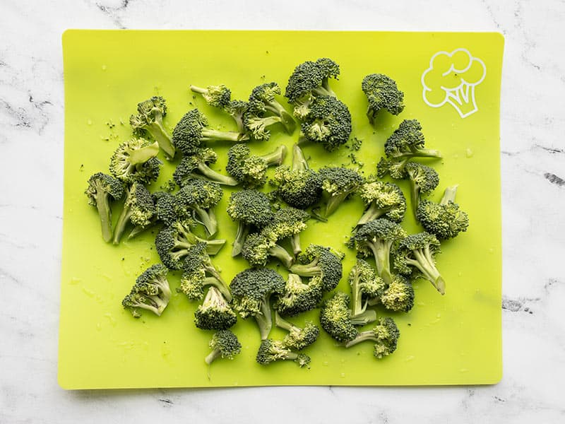 Chopped broccoli florets on a green cutting board