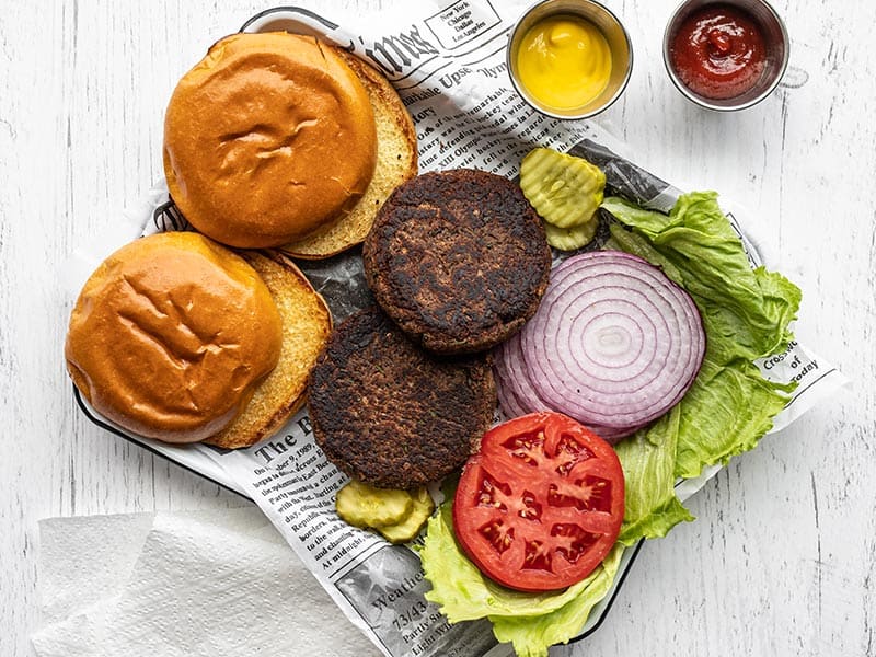 Black Bean burgers on a tray with buns, toppings, ketchup and mustard.