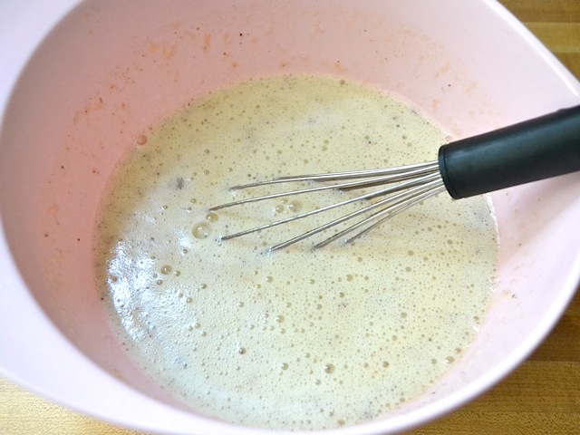 milk added to custard ingredients in mixing bowl and whisked with whisk  