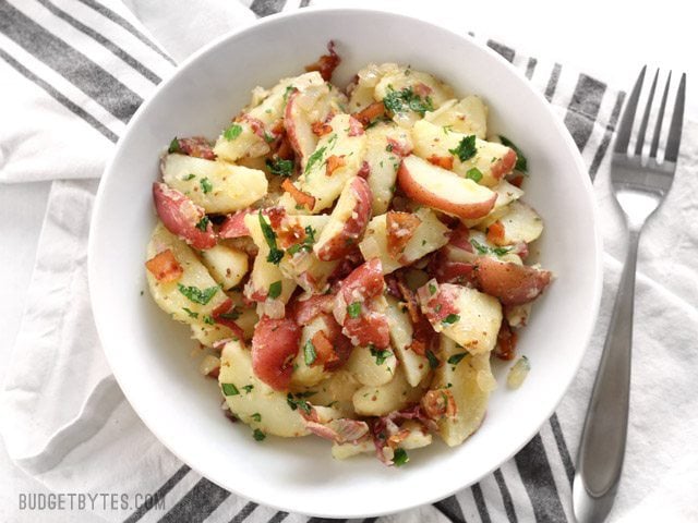 Overhead view of a bowl full of German Potato Salad on a striped napkin