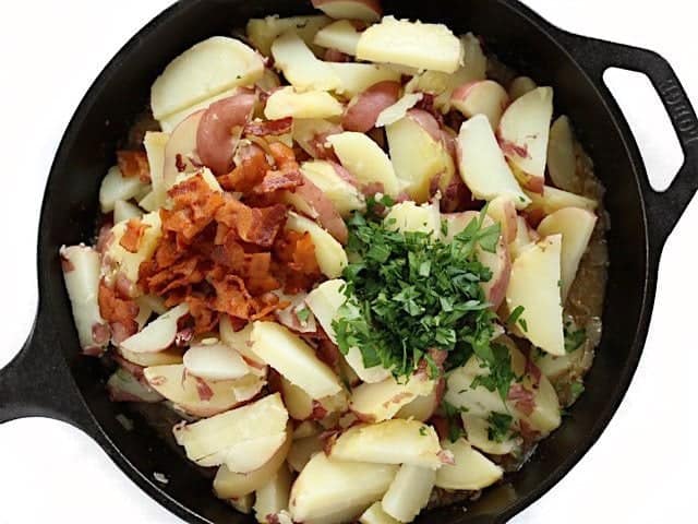 Cooked potatoes, bacon, and parsley added to dressing in the cast iron skillet
