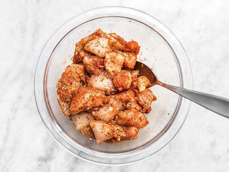 Seasoned cubed chicken with Cajun seasoning in a glass bowl