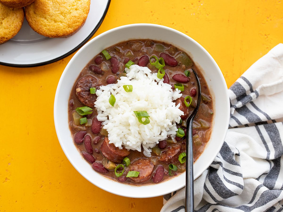 Overhead view of a bowl of quickie red beans and rice with corn muffins on the side